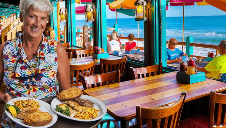 waiter holding plates of food in beachside restaurant