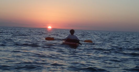 person watching a sunset from a kayak